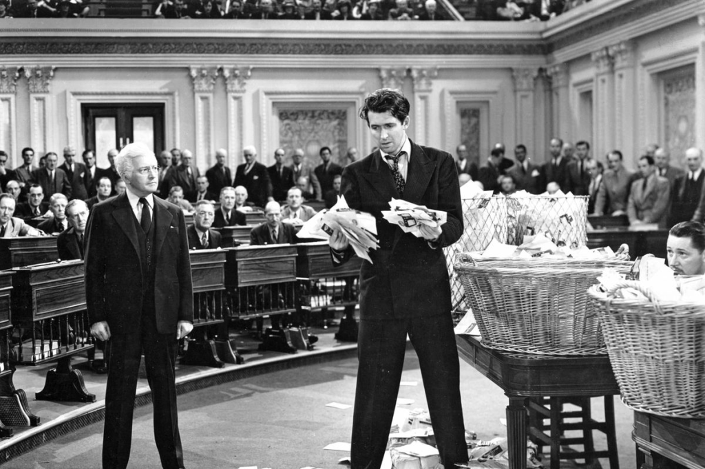 Still from Mr. Smith Goes to Washington. Claude Raines watches an incredulous James Stewart pulling letters from baskets on the Senate floor.