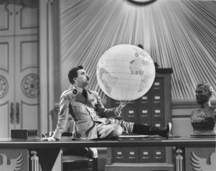 Charlie Chaplin as Adenoid Hynkel, sitting on his desk and balancing a globe on his hand.