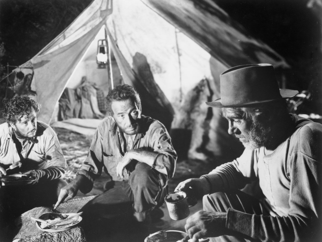 The Treasure of the Sierra Madre. Humphrey Bogart, Tim Holt, and Walter Huston sit around a campfire to eat.