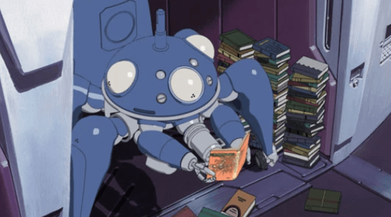 A blue Tachikoma robot tank sits in his charging station/berth reading a hardcover book held in their pincer-like gun hands. Three stacks of books almost as tall as the Tachikoma sit next to them.